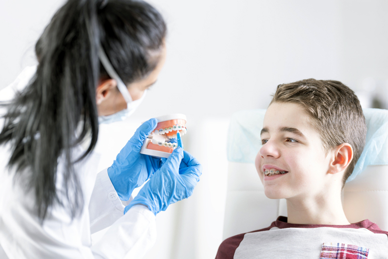 boy receiving instruction on how to clean teeth with braces