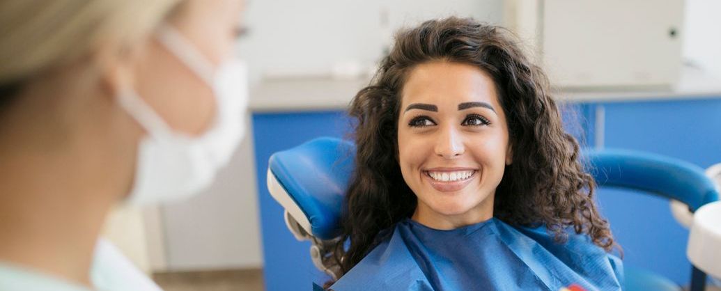 Attractive young Caucasian woman talking to orthodontist staff